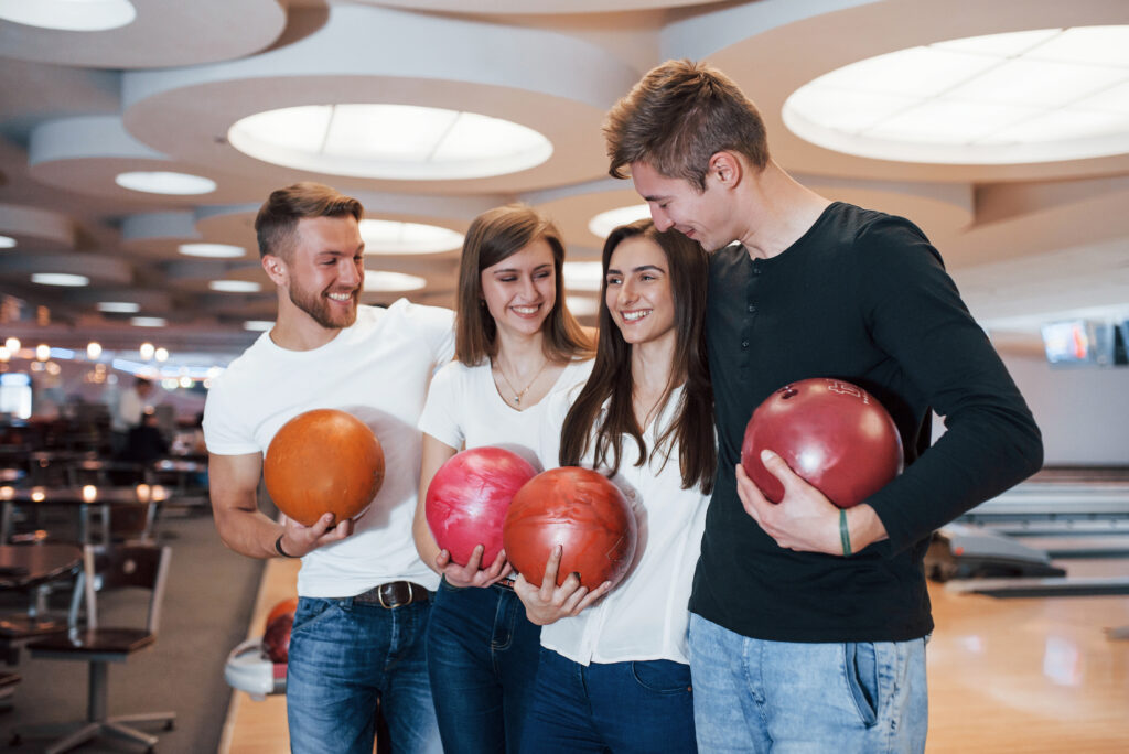 Double date. Young cheerful friends have fun in bowling club at their weekends.